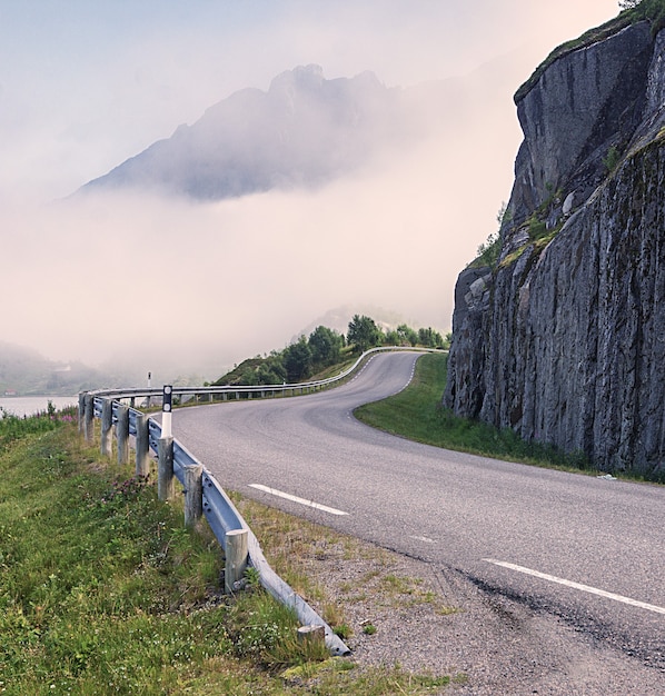 道路は、ノルウェーの山に向かって崖の周りを曲がっています。