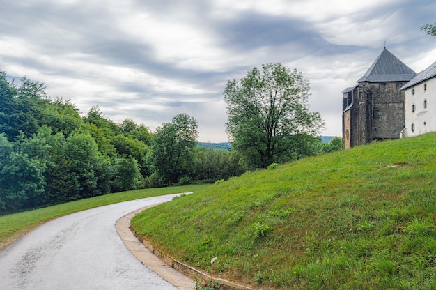 A road leading to a house with a hill in the background