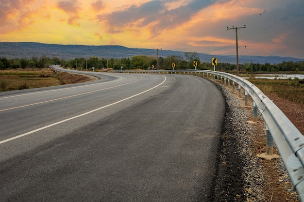 The road leads to the beautiful mountains and sky at sunset 