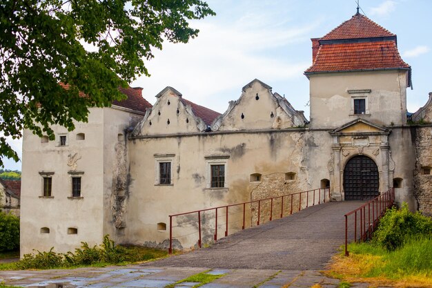 Road leads over viaduct to ancient castle with tiling roof and closed door surrounded