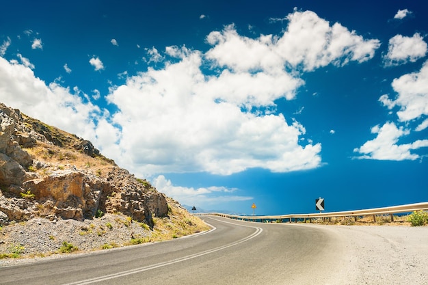 Road in the mountains and dark blue sky with white clouds. Crete island, Greece.