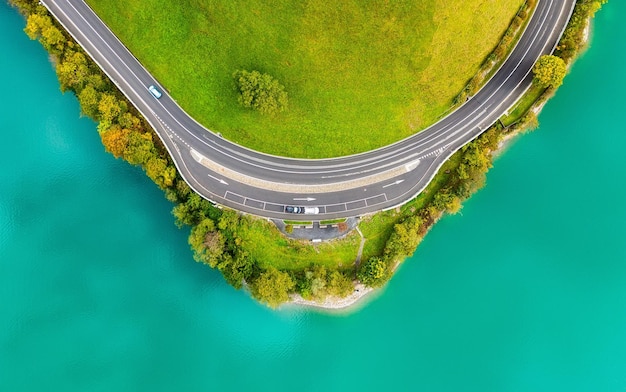 The road near turquoise lake Aerial landscape The road by the lake in Switzerland Summer landscape from the air Forest and road with curves