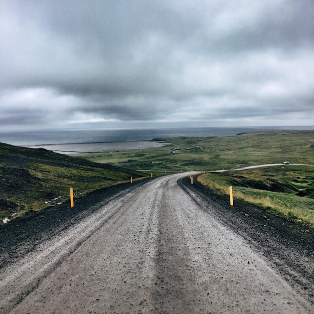 Photo road passing through field against storm clouds