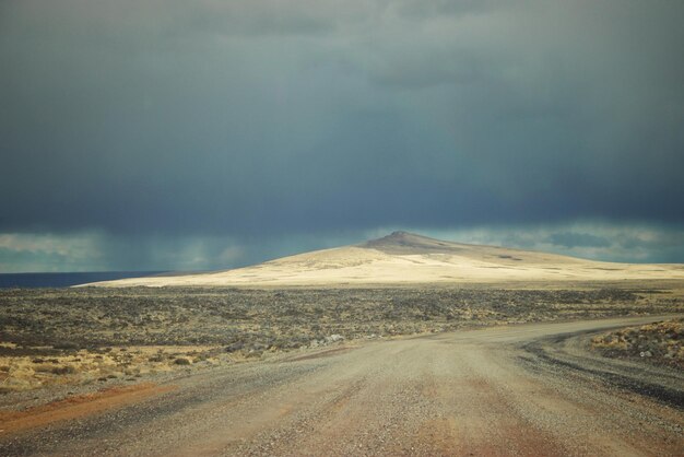 Photo road passing through land against cloudy sky