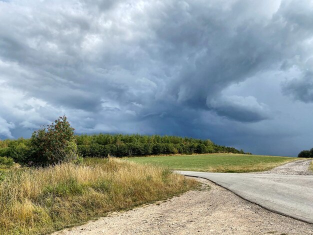 Foto strada che attraversa il paesaggio contro un cielo nuvoloso