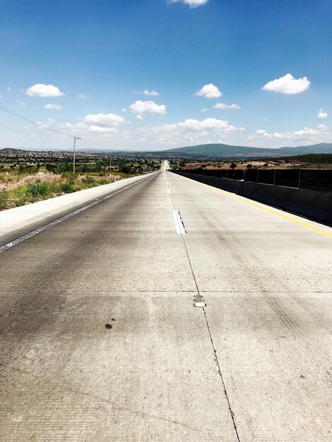 写真 空に照らされた風景を横断する道路