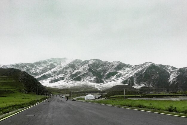 Road passing through mountains against clear sky