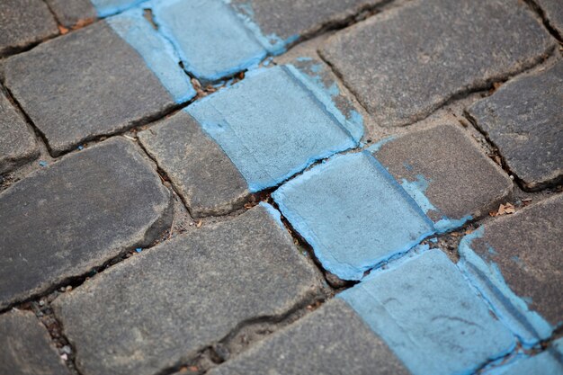 Road paved with granite stones with blue markup line. Closeup shot