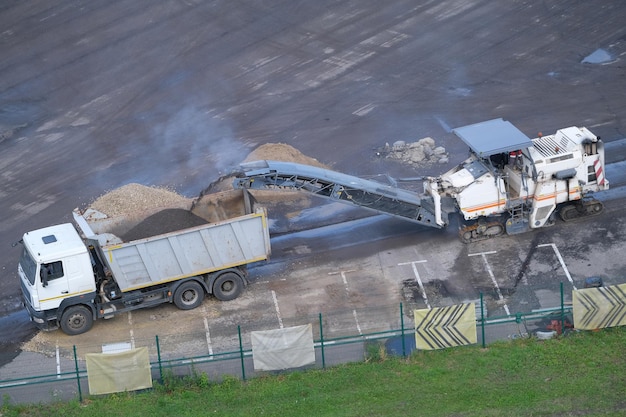 Road removal milling machine loads recycled asphalt to truck,\
asphalt pavement dismantling, top view