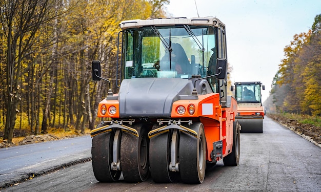 Road repair compactor lays asphalt heavy special machines\
asphalt paver in operation side view closeup