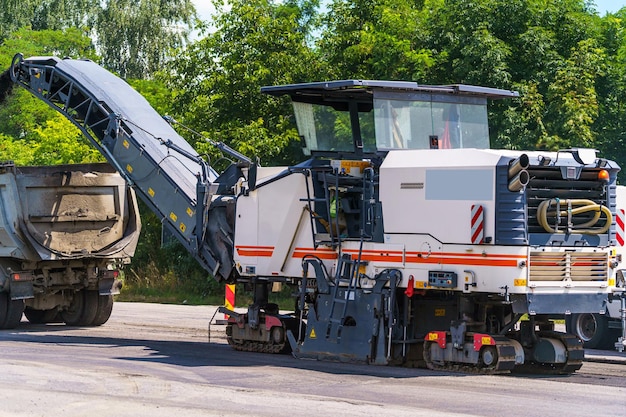 写真 道路修理重い特殊機械運転中のアスファルトペーバー側面図クローズアップ