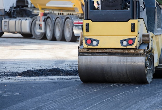 Road roller and asphalt paving machine at construction\
site