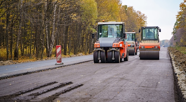 Road roller flattening new asphalt. heavy vibration roller at
work paving asphalt, road repairing. selective focus.