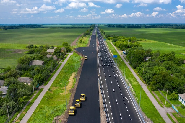 新しいアスファルト道路の航空写真を構築するロードローラー