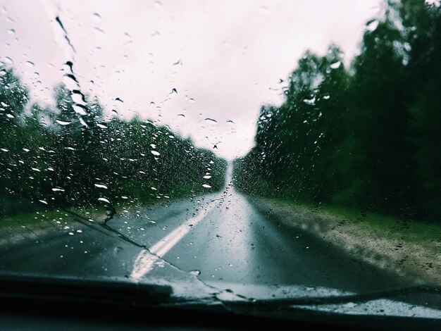 Road seen through wet glass window in rainy season