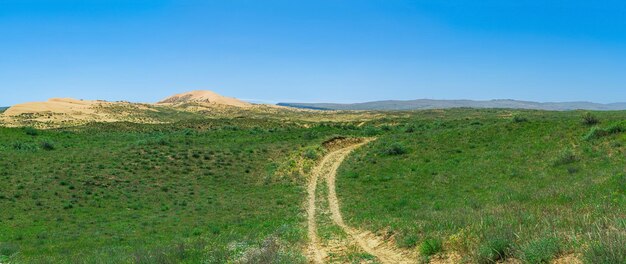 Дорога в полупустынном степном ландшафте в окрестностях Сарыкумского бархана