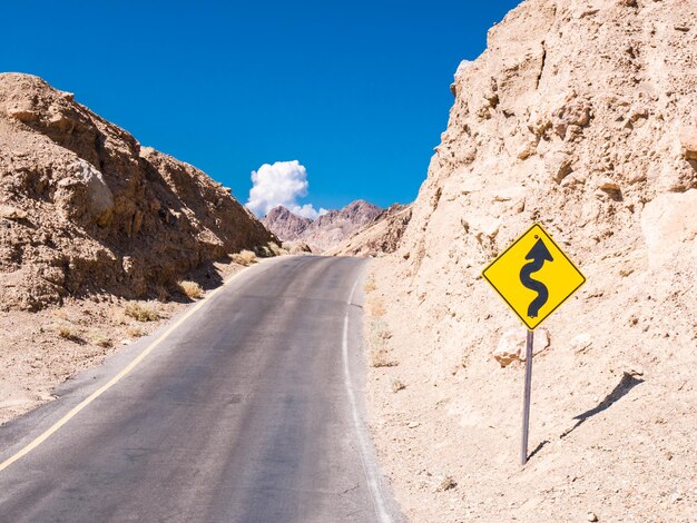 Road sign against mountains and blue sky