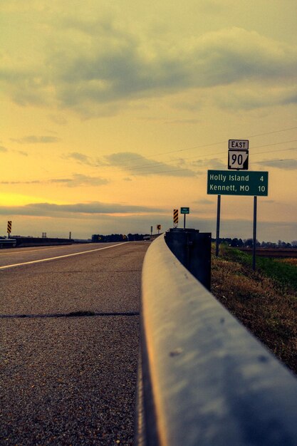 Road sign against sky during sunset