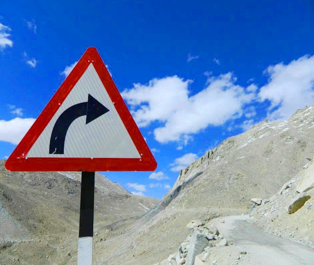 Road sign by mountains against sky