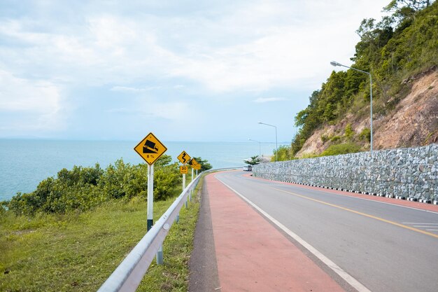 Road sign by sea against sky