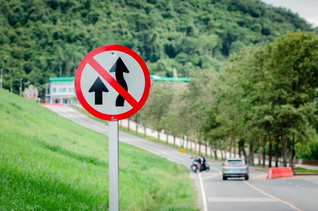 Road sign by street against trees in city