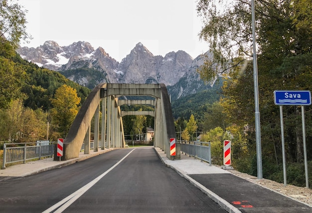 Road sign by trees against mountain range