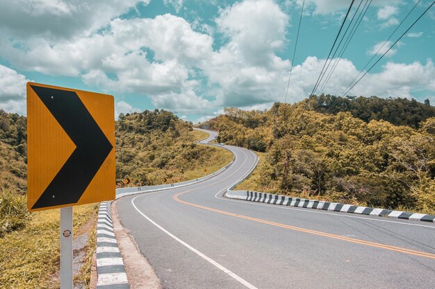 Road sign by trees against sky