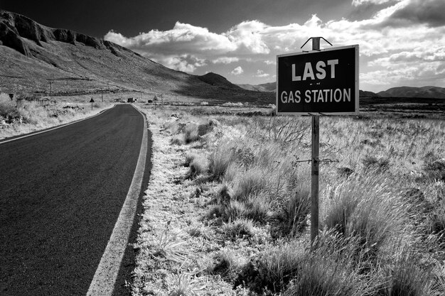 Road sign on field against sky