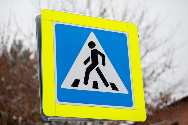 A road sign of a pedestrian crossing in close-up. A sign with a reflective coating is installed