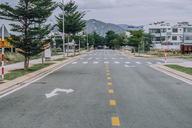 道路標識黄色点線歩行者用クロスマーク白ペイント矢印方向前方右左アスファルト静かな空の市街地での脱出通りの山の背景不動産はコンセプトを変更します