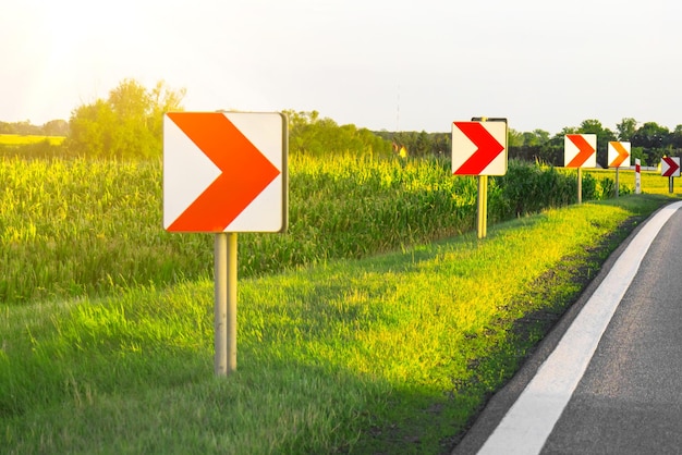 Road signs in european style warn of a sharp turn on a narrow road a sharp turn