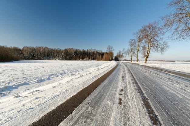 明るい空に照らされた雪に覆われた風景の道路