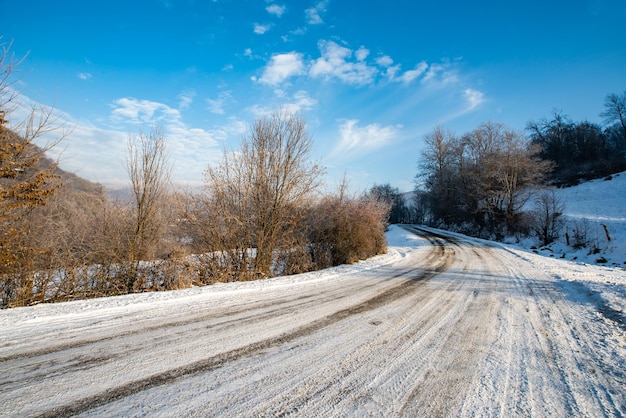 Road in the snow near the forest on a cold winter day