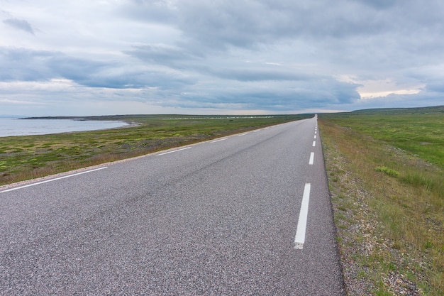 The road stretches into the distance on a background of green meadows