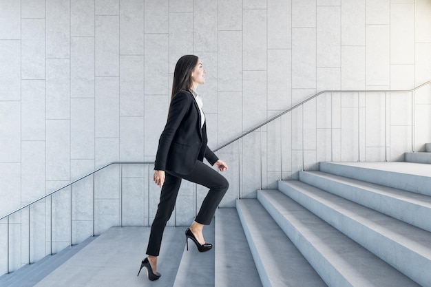 Road to success concept with businesswoman climbing the stairs in modern loft style hall