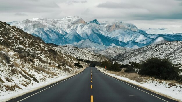 Road surrounded by hills with rocky mountains covered in the snow