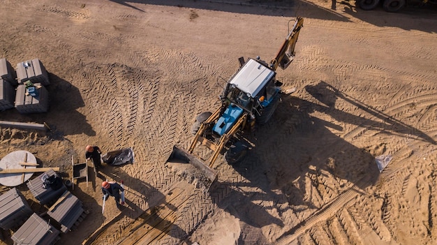 Road transport works repair laying a thick layer of asphalt concrete large trucks tractors road markings red and yellow road signs heaps of sand earth old buildings people make the way