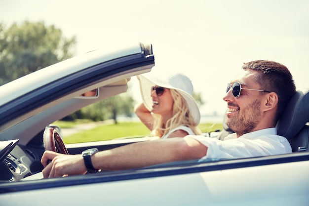 road trip, travel, dating, couple and people concept - happy man and woman driving in cabriolet car outdoors