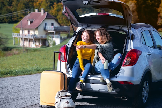 road trip - Twee lachende tienermeisjes die in de koffer zitten