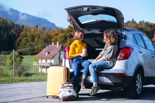 поездка - Две улыбающиеся девушки подростка сидят в багажнике