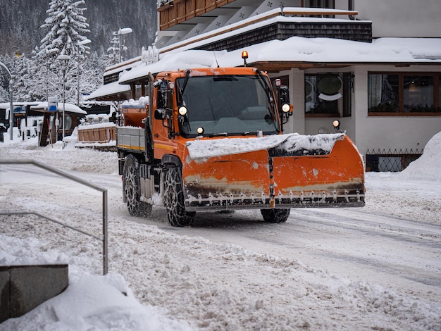 写真 雪が降る日に白く塗られた道路で作業中の道路車両の雪掃除機