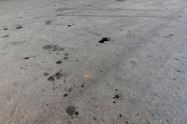 A road for vehicles covered with stains and pollution from oil and fuel of cars