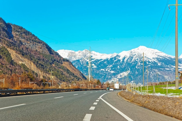 Road view on electricity transmission lines in Switzerland in winter. Switzerland is a country in Europe. Switzerland has a high mountain range; from the Alps to Jura mountains.