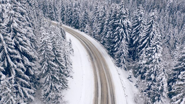 Road in the winter mountain forest. Drone view.