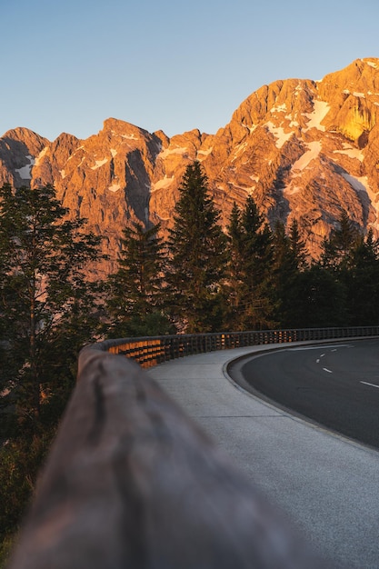 Photo a road with a beautiful mountain in the background during sunrise in alps