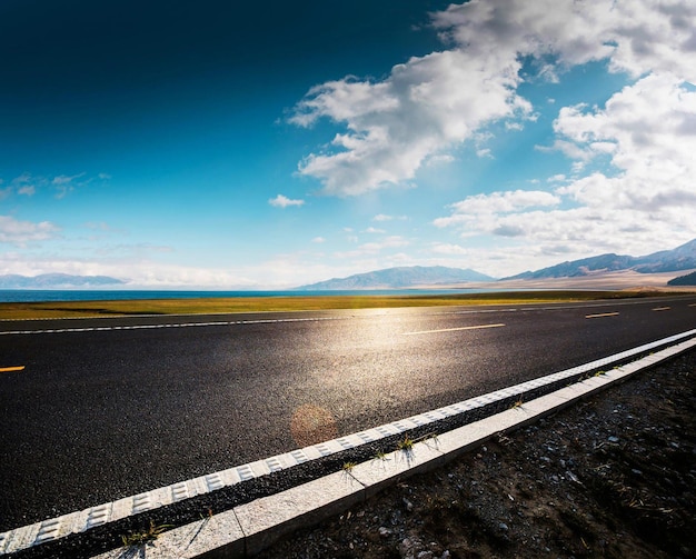 Foto una strada con un cielo blu e montagne sullo sfondo