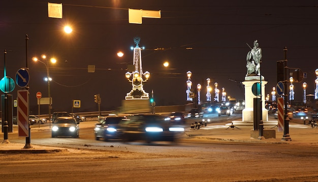 A road with bright lanterns and burning garlands in St. Petersburg. Cars drive with headlights on