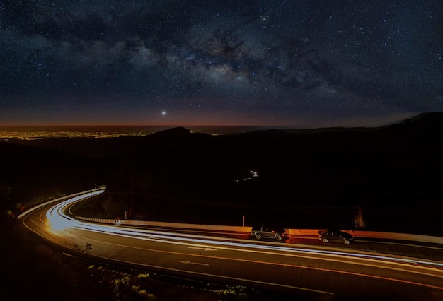 A road with a starry sky and a road with a few cars on it