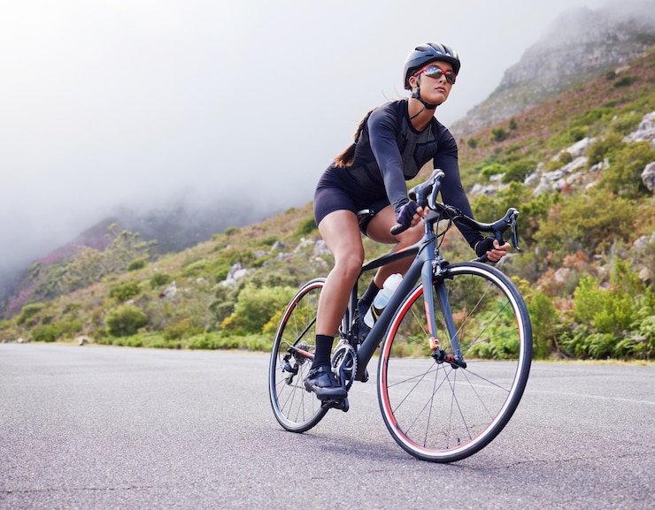 Photo road woman and cycling with fitness health and training for wellness cardio and endurance female person biker and cyclist with workout street and practice with a helmet glasses and exercise