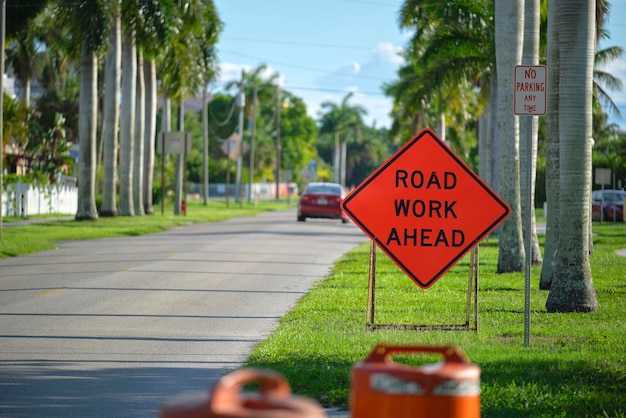 Road work ahead sign on street site as warning to cars about construction and utility works